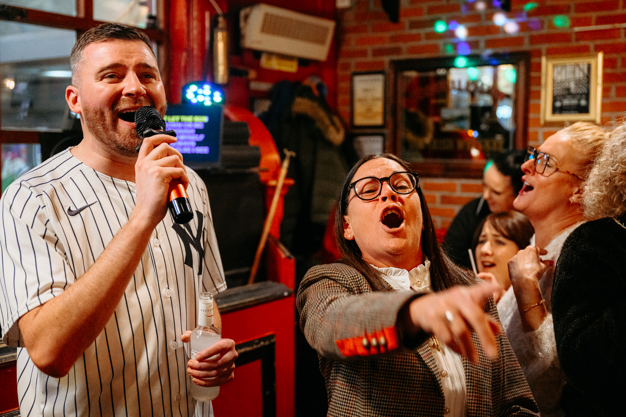 Woman with dark hair pointing at camera inside Coopers pub